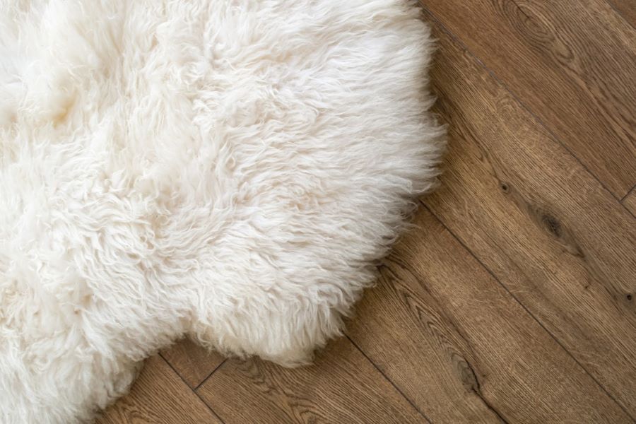 cream sheepskin rug on a dark brown wooden floor